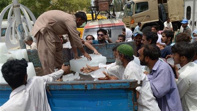 Người dân Pakistan nhận nước đá bên ngoài một bệnh viện ở Karachi hôm 24-6 - Ảnh: AFP