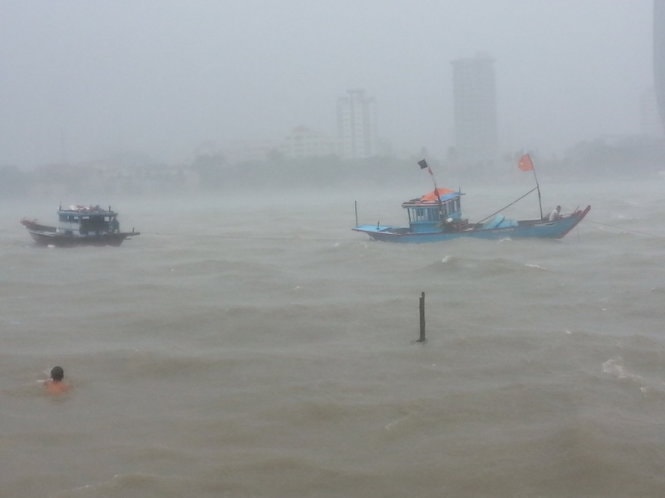 Tàu thuyền neo đậu trên sông Hàn bị sóng nước đánh mạnh, nhiều người dân đang cố gắng kéo vào bờ - Ảnh: PHAN THÀNH