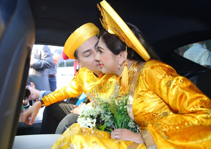 Cô dâu cổ đeo đầy vàng, hạnh phúc khi được chú rể hôn má trên xe hoa.