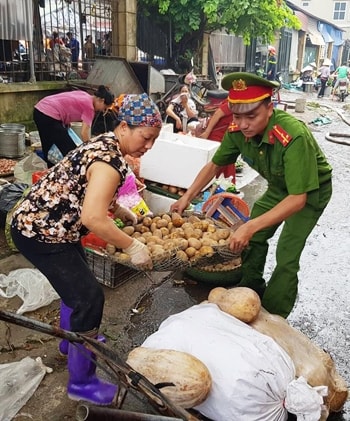 Công an giúp tiểu thương di dời hàng hóa khỏi đám cháy. Ảnh: Gia Chính.