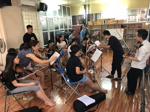 Nhạc trưởng Lê Quang Minh (áo đen, phải) hướng dẫn các nhạc công nhí tập luyện.
