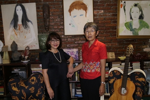 Michiko Yoshii bên ca sĩ Trịnh Vĩnh Trinh ở nhà riêng của Trịnh Công Sơn năm 2018. Trên tường treo bức tranh cố nhạc sĩ từng vẽ bà (giữa).