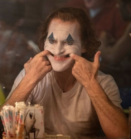 Một cảnh Joaquin Phoenix kết hợp động tác hình thể và hóa trang để gây sợ hãi. Ảnh: Warner Bros.