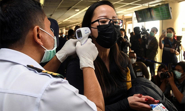 Nhân viên y tế đo thân nhiệt hành khách tại sân bay quốc tế Don Mueang, Bangkok, Thái Lan hôm 25/1. Ảnh: Reuters.