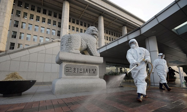 Nhân viên kiểm dịch phun khử trùng tại tòa nhà quốc hội Hàn Quốc ở Seoul hôm 24/2. Ảnh: AFP.