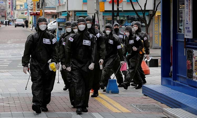 Binh sĩ Hàn Quốc mặc đồ bảo hộ đi khử trùng các tòa nhà hôm 15/3. Ảnh: Reuters.