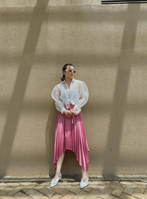 Sơ mi trắng trong suốt được Yến Nhi sử dụng một cách tinh tế cùng áo hai dây tiệp màu và chân váy xếp ly gam hồng đậm chất nữ tính.