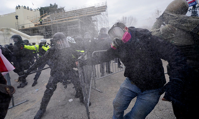 Cảnh sát chống bạo động dùng dùi cui và hơi cay đẩy lùi người biểu tình đang cố phá vỡ hàng rào an ninh bên ngoài nhà quốc hội Mỹ, ngày 6/1. Ảnh: WP.