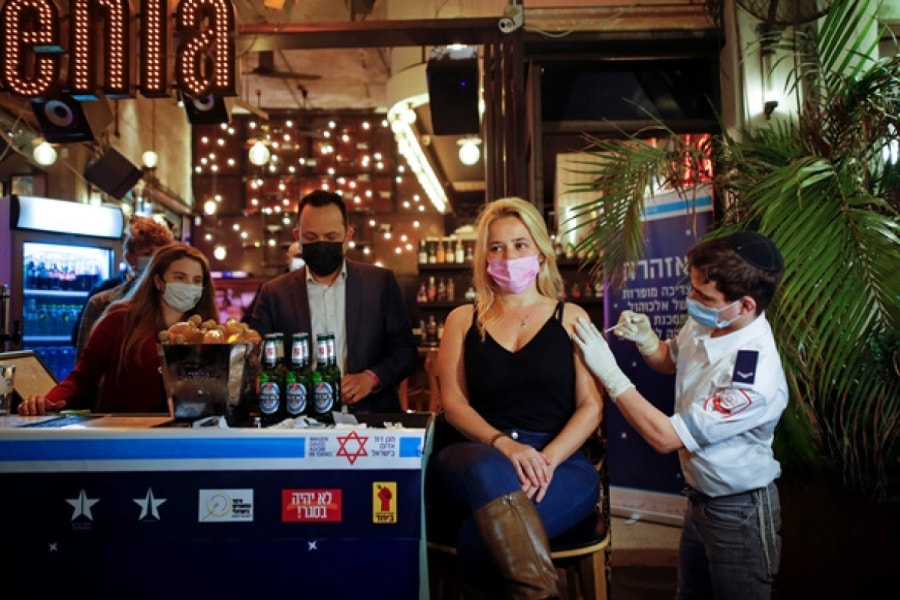 Một nhân viên y tế ở Tel Aviv, Israel tiêm vaccine ngừa Covid-19 cho người dân ngày 18/2. Tất cả người đến tiêm chủng được quán bar địa phương mời nước uống miễn phí. Ảnh: Reuters