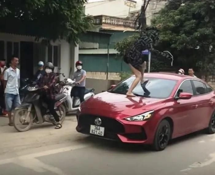 Người phụ nữ nhảy lên đầu xe ô tô đạp vỡ kính (Ảnh cắt từ clip)