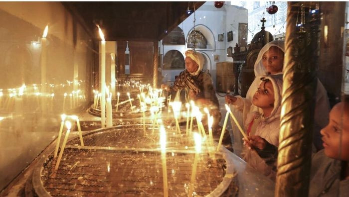 Người hành hương và du khách thắp nến bên trong Nhà thờ Giáng sinh tại thành phố Bờ Tây Brthlehem, Palestine. Ảnh: AFP