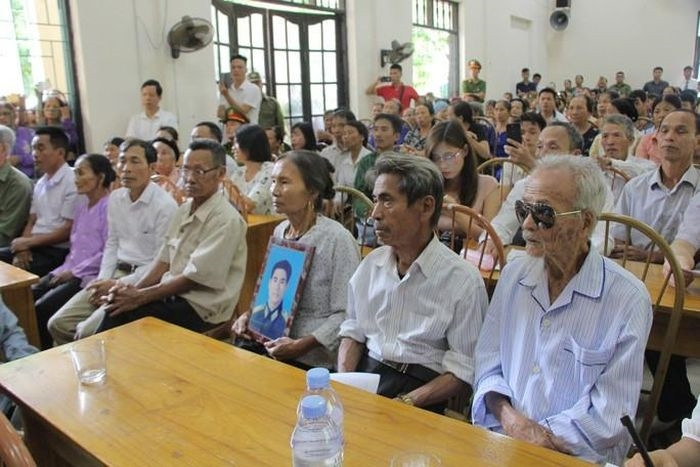 Vợ ông Trần Trung Thám ôm di ảnh của chồng ngồi cạnh ông Trần Ngọc Chinh (giữa) và ông Khổng Văn Đệ tại buổi cải chính công khai hồi tháng 10/2019.