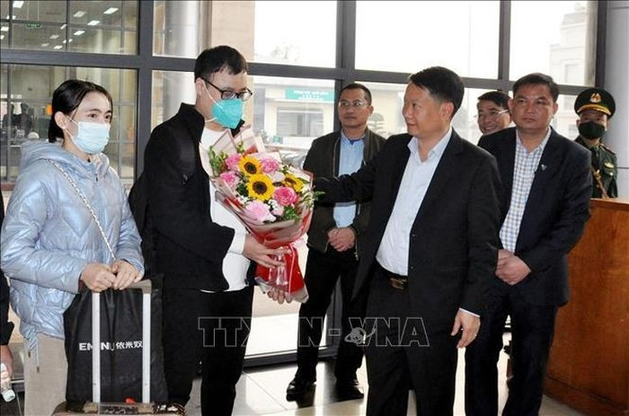 Chủ tịch UBND thành phố Móng Cái Hồ Quang Huy tặng hoa, chúc mừng những người đầu tiên xuất, nhập cảnh qua hai cửa khẩu. Ảnh: TTXVN phát