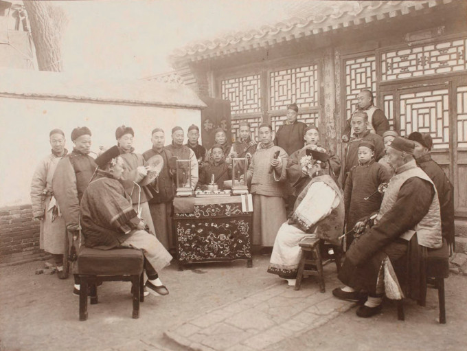 Hình ảnh ở hôn lễ của người dân tộc Mãn, chụp thập niên 1890. Tân lang và tân nương ngồi đối diện nhau, xung quanh là những người chơi nhạc cụ.