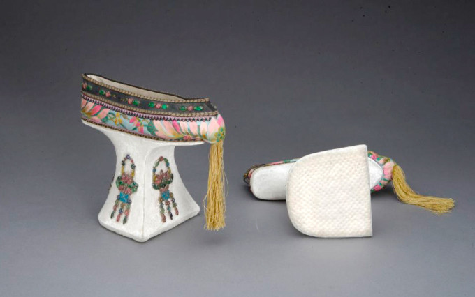 Đôi giày cao 17 cm, dài 21,5 cm, từng là đồ vật của phụ nữ ở hậu cung thời Thanh. Phần trên may từ vải lụa, thêu hoa sinh, đính đá. Mũi giày trang trí bằng chỉ thêu.