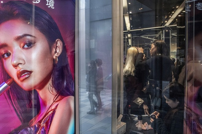 Một khách hàng trẻ đang thử trang điểm trong cửa hàng mỹ phẩm MAC ở Bắc Kinh, tháng 7/2023. Ảnh: Bloomberg