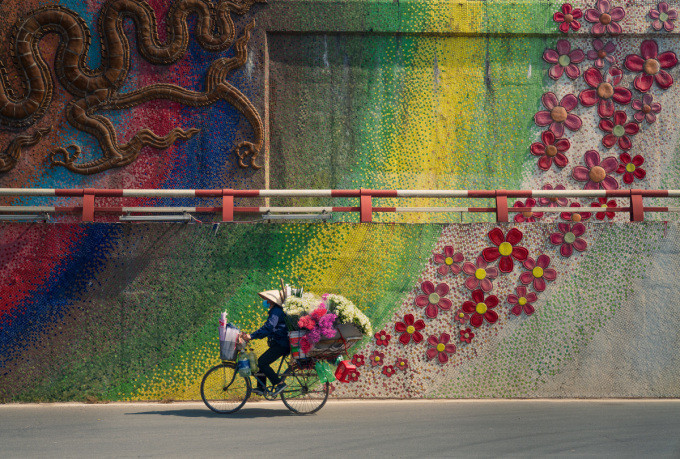 Người phụ nữ đạp xe chở hoa bán dạo đi qua con đường gốm sứ ở Hà Nội. Ảnh: Nguyễn Phúc Thành