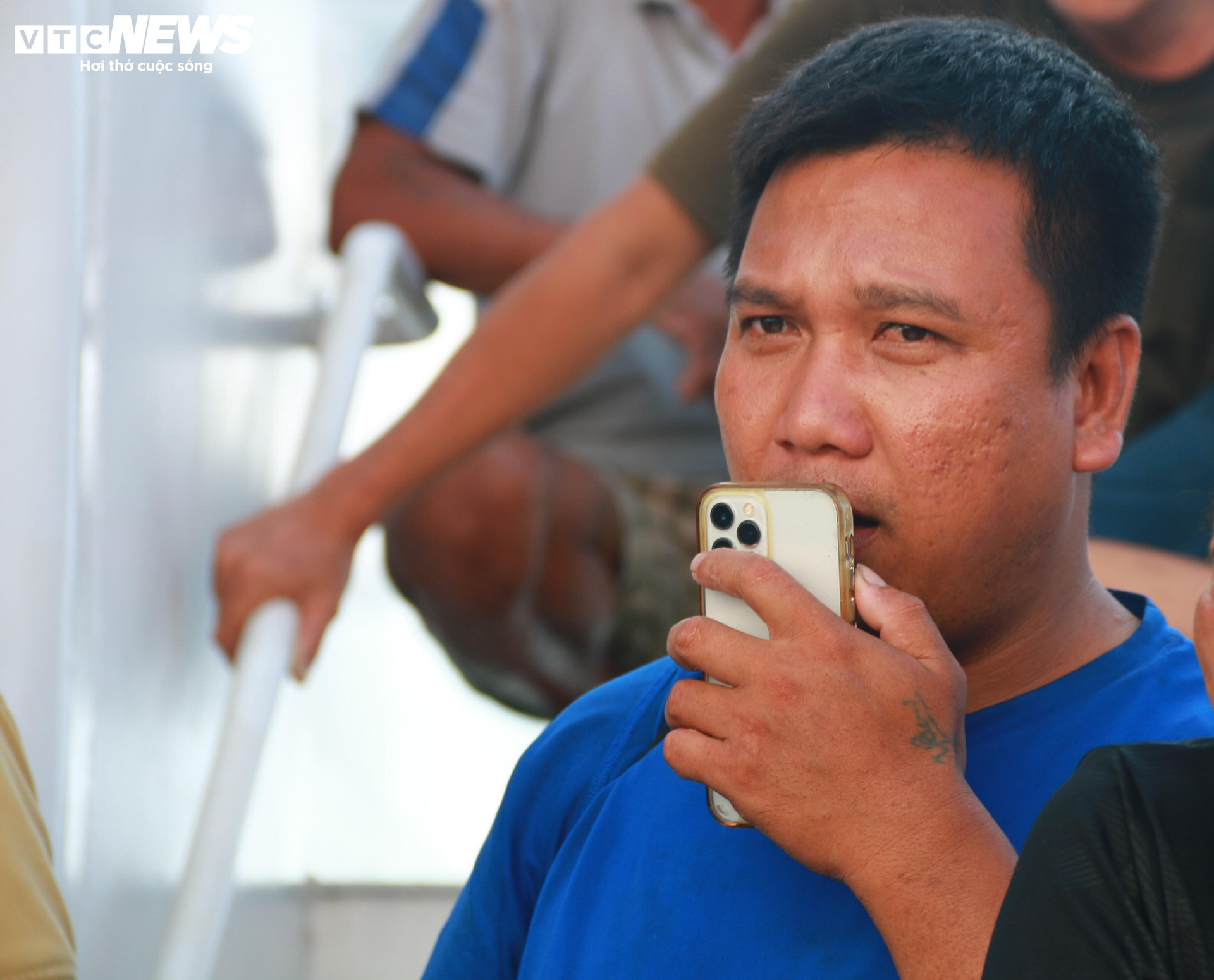 Một thuyền viên tranh thủ mượn điện thoại gọi điện cho người thân trong lúc chờ rời khỏi tàu 467 Hải quân.