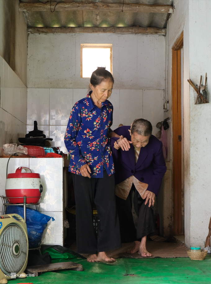 Hat (wearing the flower shirt) helps her 122-year-old mother to the bathroom in their home in northern Hai Duong Province, Oct. 30, 2023. Photo by VnExpress/ Hai Hien