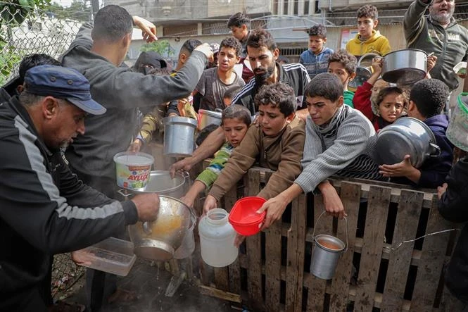 Người dân nhận thức ăn cứu trợ tại thành phố Rafah, Dải Gaza. (Ảnh: THX/TTXVN)