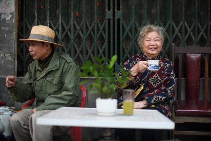 Nghệ sĩ Lê Mai ngồi uống nước bên hàng xóm ở đầu ngõ 20 Phan Đình Phùng, Hà Nội. Ảnh: Giang Huy