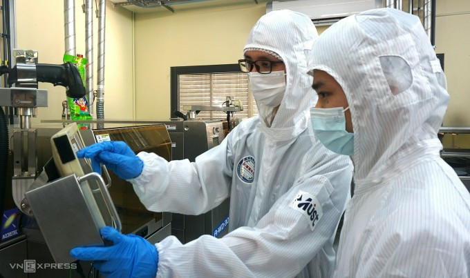 Hai học viên người Việt đang vận hành máy tạo khuôn chip bán dẫn tại phòng thực hành Đại học Minh Tân. Ảnh: Lệ Nguyễn