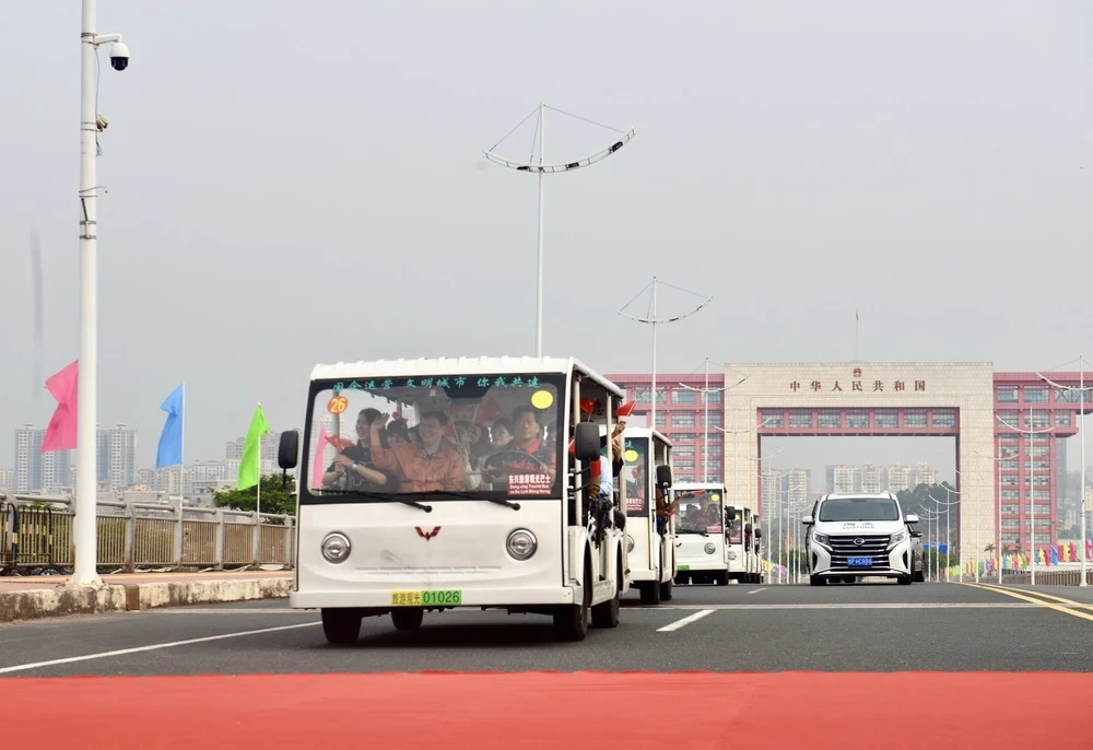 Các xe trung chuyển (xe điện) chở khách du lịch xuất cảnh đi qua vạch phân quảng cầu Bắc Luân II. (Ảnh: Thanh Vân/TTXVN)