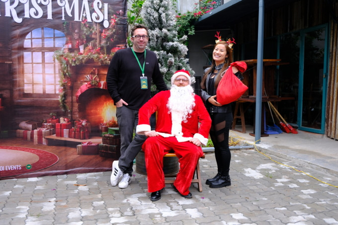 Gary Devitt (in black t-shirt) takes a photo with his wife and a man in a Santa Claus costume. Photo by VnExpress/Quynh Nguyen