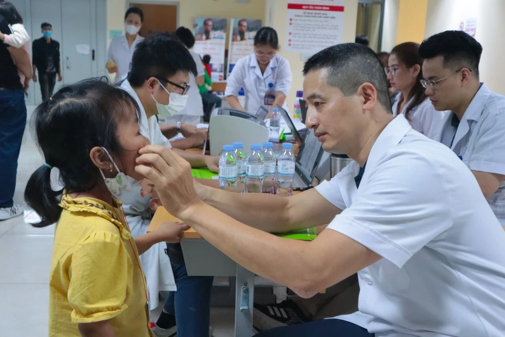 Bác sỹ khám cho trẻ mắc dị tật khe hở môi, vòm miệng. (Ảnh: PV/Vietnam+)