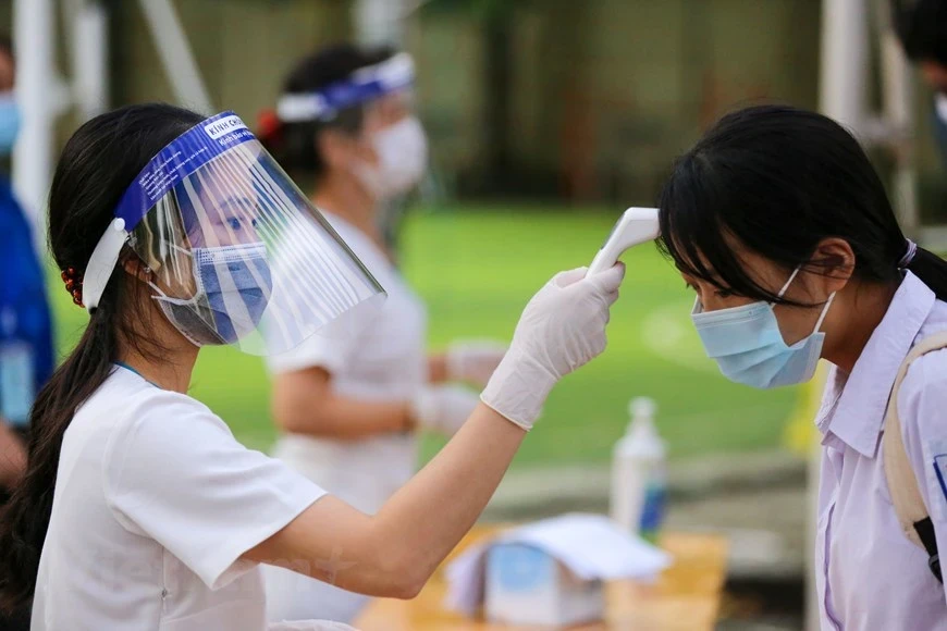 Nhân viên y tế học đường kiểm tra sức khỏe học sinh trong giai đoạn dịch COVID-19. (Ảnh: Minh Sơn/Vietnam+)