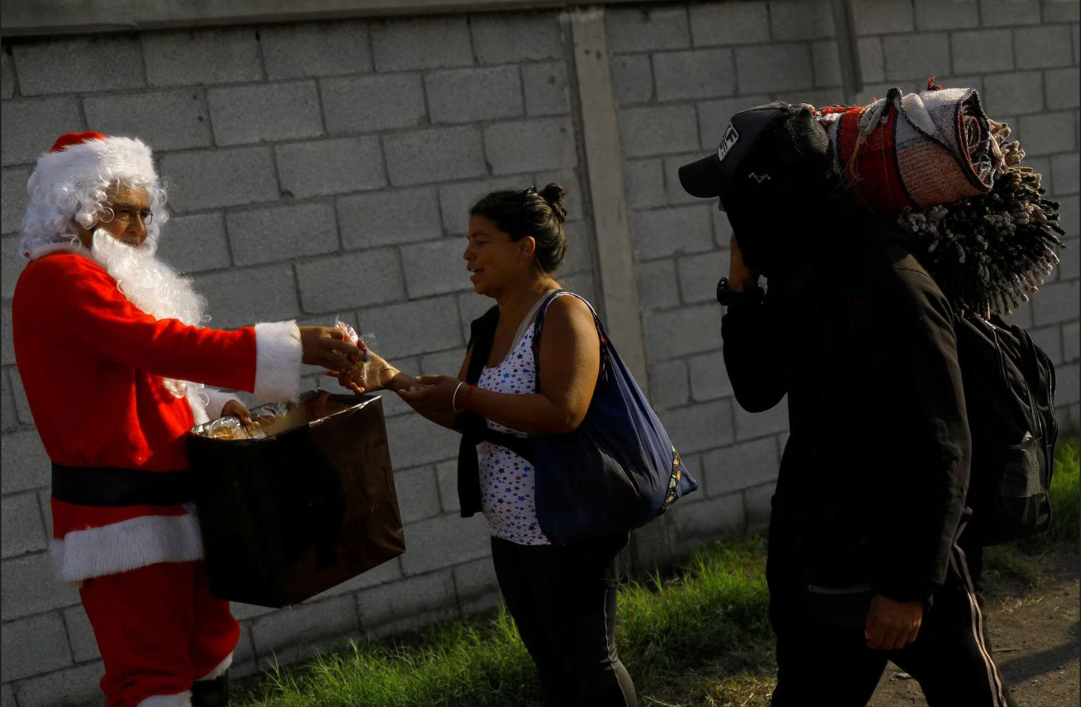 Ông Miguel Angel hóa trang thành ông già Noel tặng kẹo cho những người di cư đang di chuyển đến Cục Hải quan và Biên phòng Mỹ ở thành phố Piedras Negras, bang Coahuila (Mexico) vào ngày 21-12 - Ảnh: REUTERS
