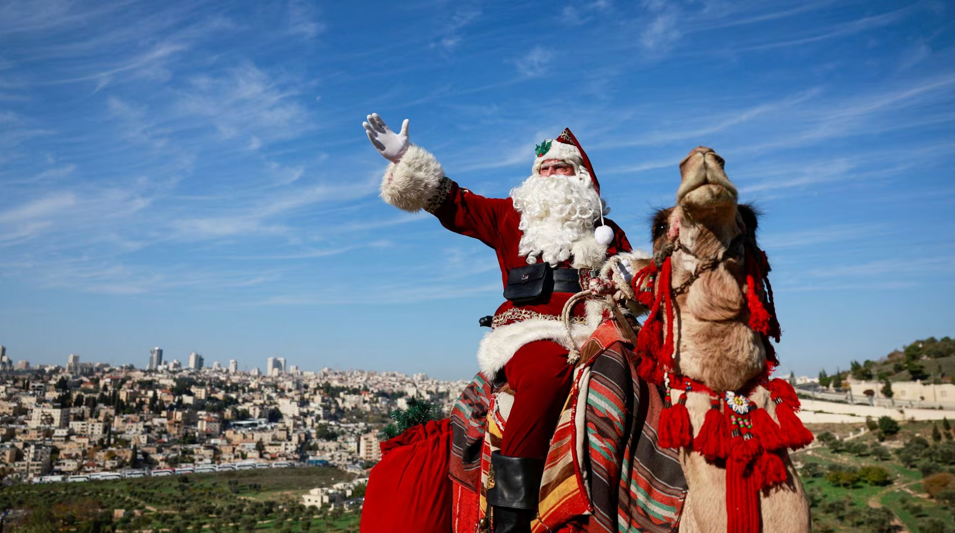 Ông Issa Kassissieh mặc trang phục ông già Noel, cưỡi lạc đà đến thăm khu rừng ô liu ở Jerusalem (Israel) vào ngày 4-12 - Ảnh: REUTERS