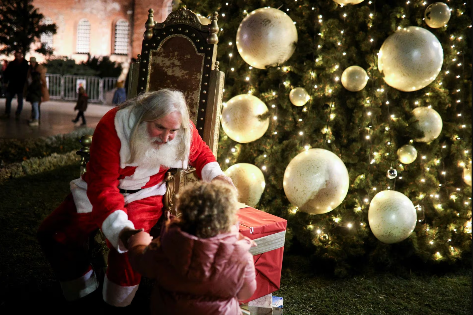 Một ông già Noel với vẻ ngoài giống hệt mô tả trong truyền thuyết trò chuyện với trẻ nhỏ cạnh cây thông khổng lồ của nhà thờ Alexander Nevsky nằm ở thủ đô Sofia, Bulgaria vào ngày 1-12 - Ảnh: REUTERS