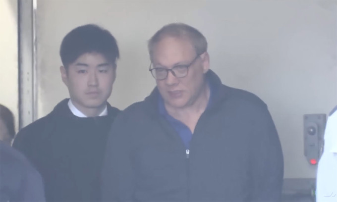 Người đàn ông Mỹ cắn tiếp viên (thứ hai từ trái sang) bị áp giải tại sân bay ở Nhật Bản ngày 16/1. Ảnh: TBS