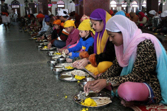 Mọi người ngồi trong hội trường lớn của Đền Vàng để ăn các bữa miễn phí. Ảnh: Aljazeera
