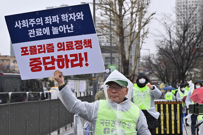 Bác sĩ Hàn Quốc giơ biểu ngữ phản đối kế hoạch tăng chỉ tiêu tuyển sinh ngành y trên đường phố Seoul, ngày 21/2. Ảnh: AFP