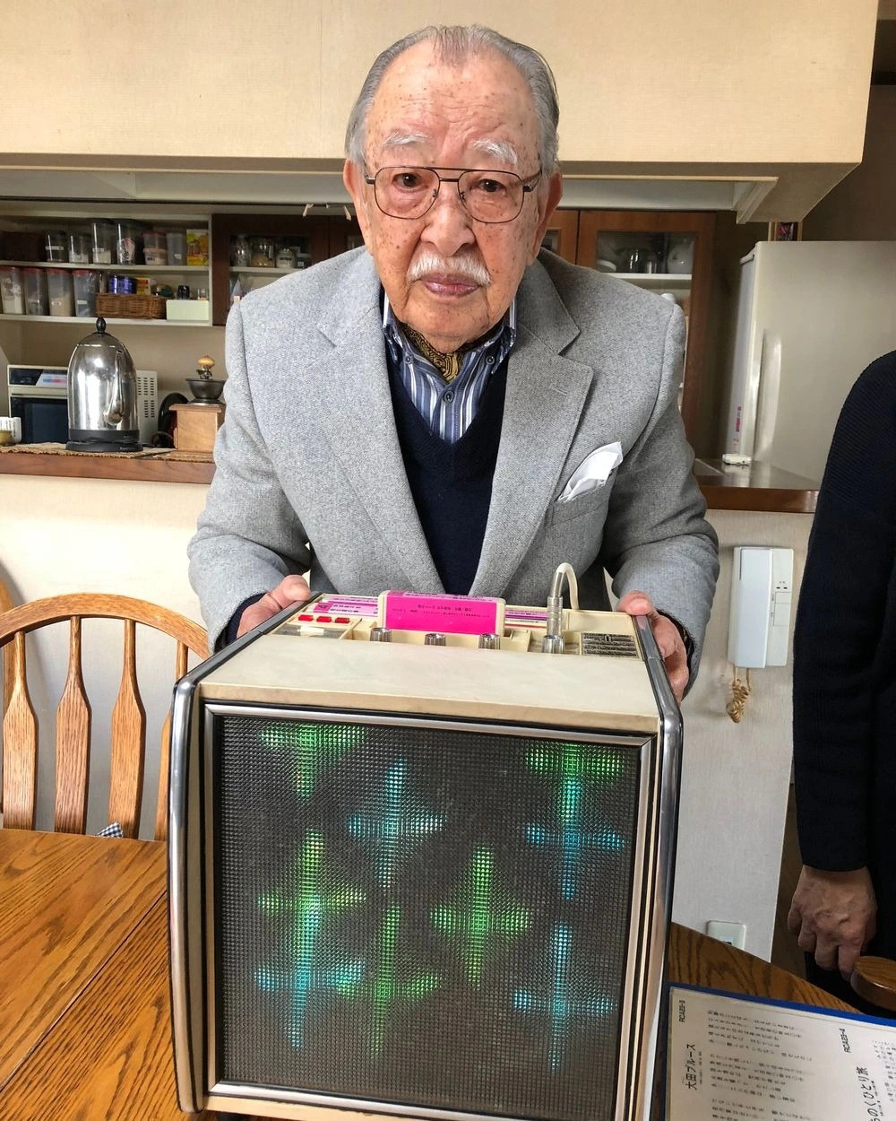 Chân dung ông Shigeichi Negishi bên cạnh chiếc máy karaoke đầu tiên trên thế giới - Ảnh: Kotaku