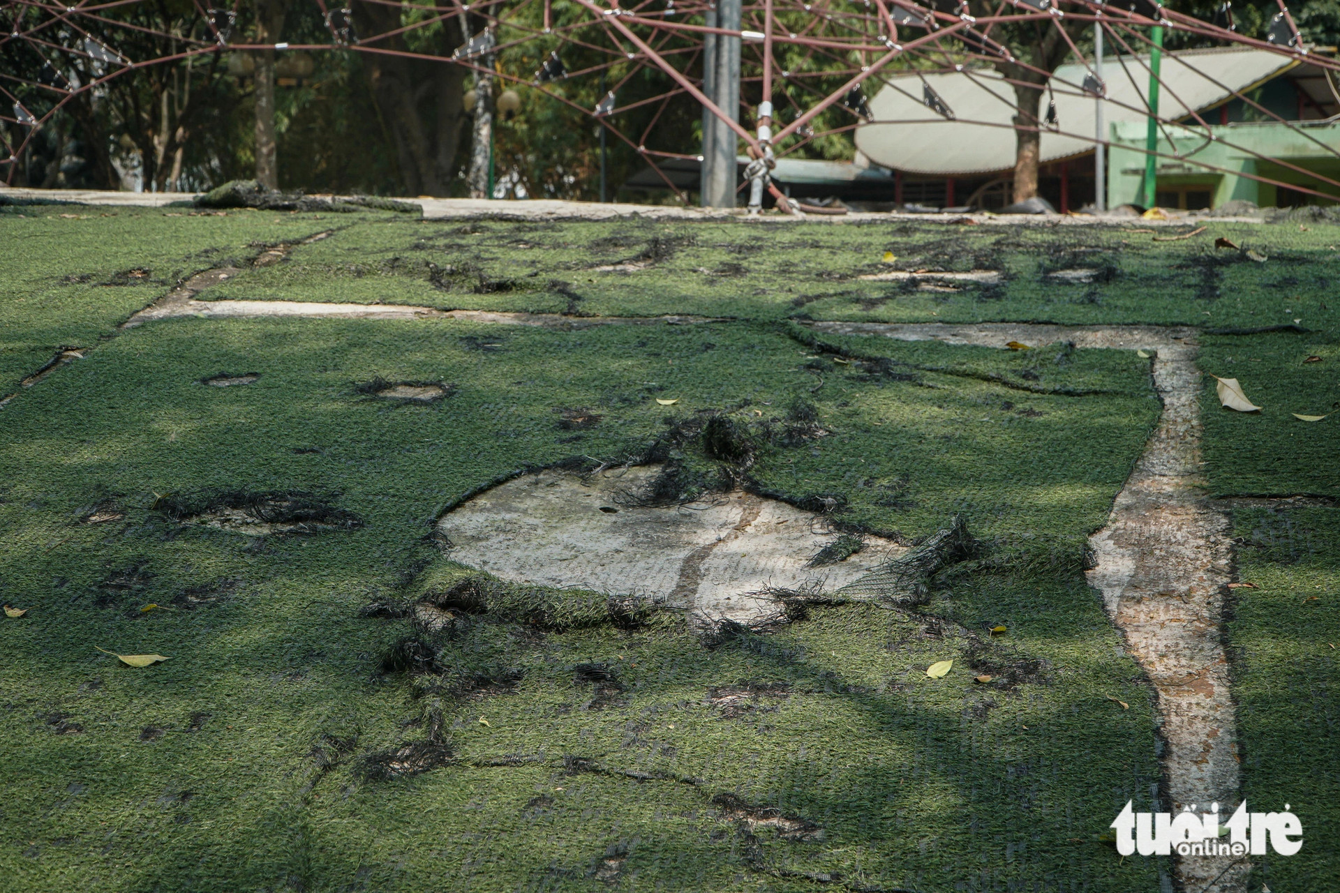 Phần cỏ nhân tạo tại công viên Cầu Giấy bong tróc, lộ ra những mảng bê tông lớn - Ảnh: PHẠM TUẤN
