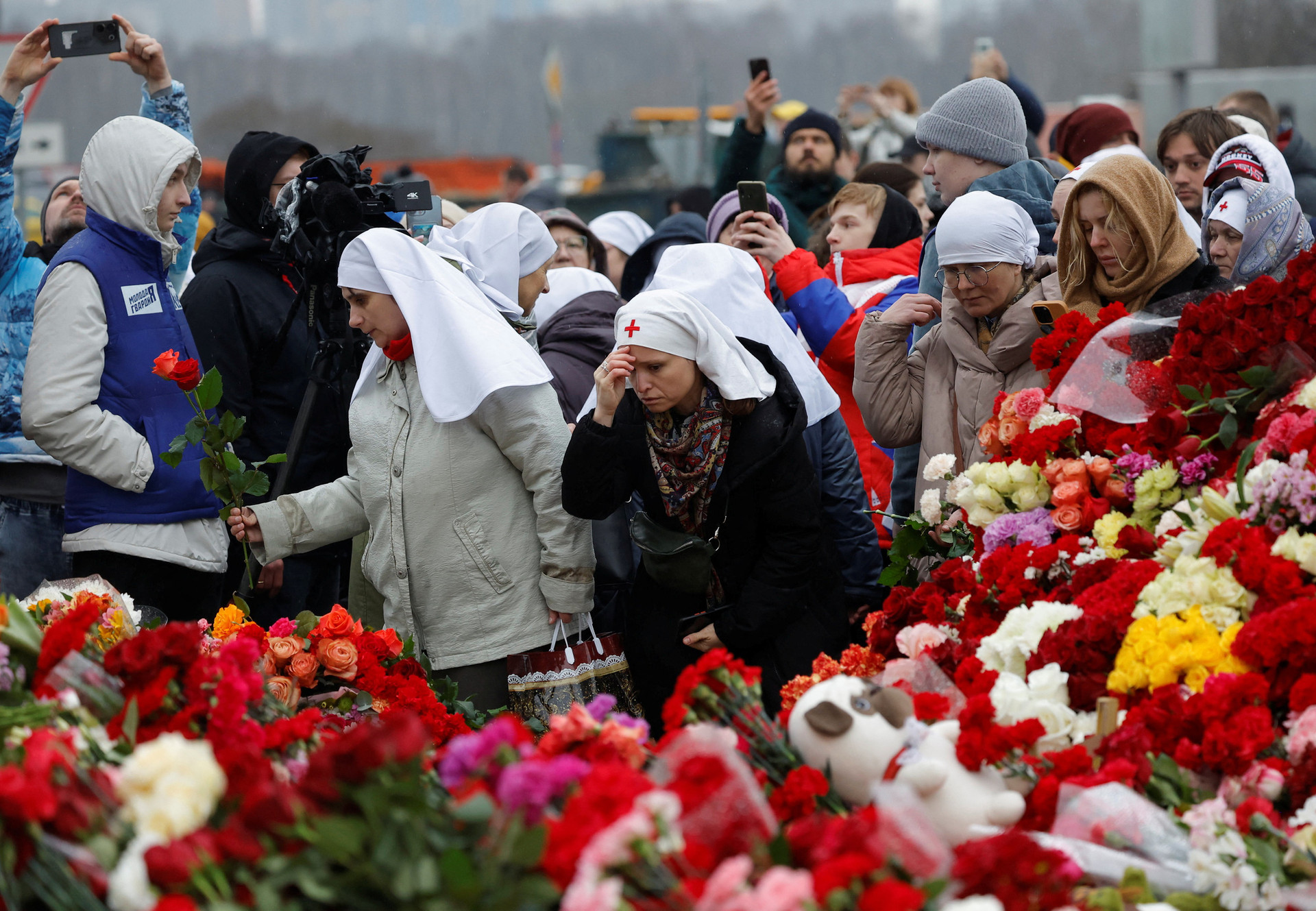 Một số nữ tu và người dân đặt hoa tưởng niệm ở khu vực Matxcơva sáng 24-3 - Ảnh: REUTERS
