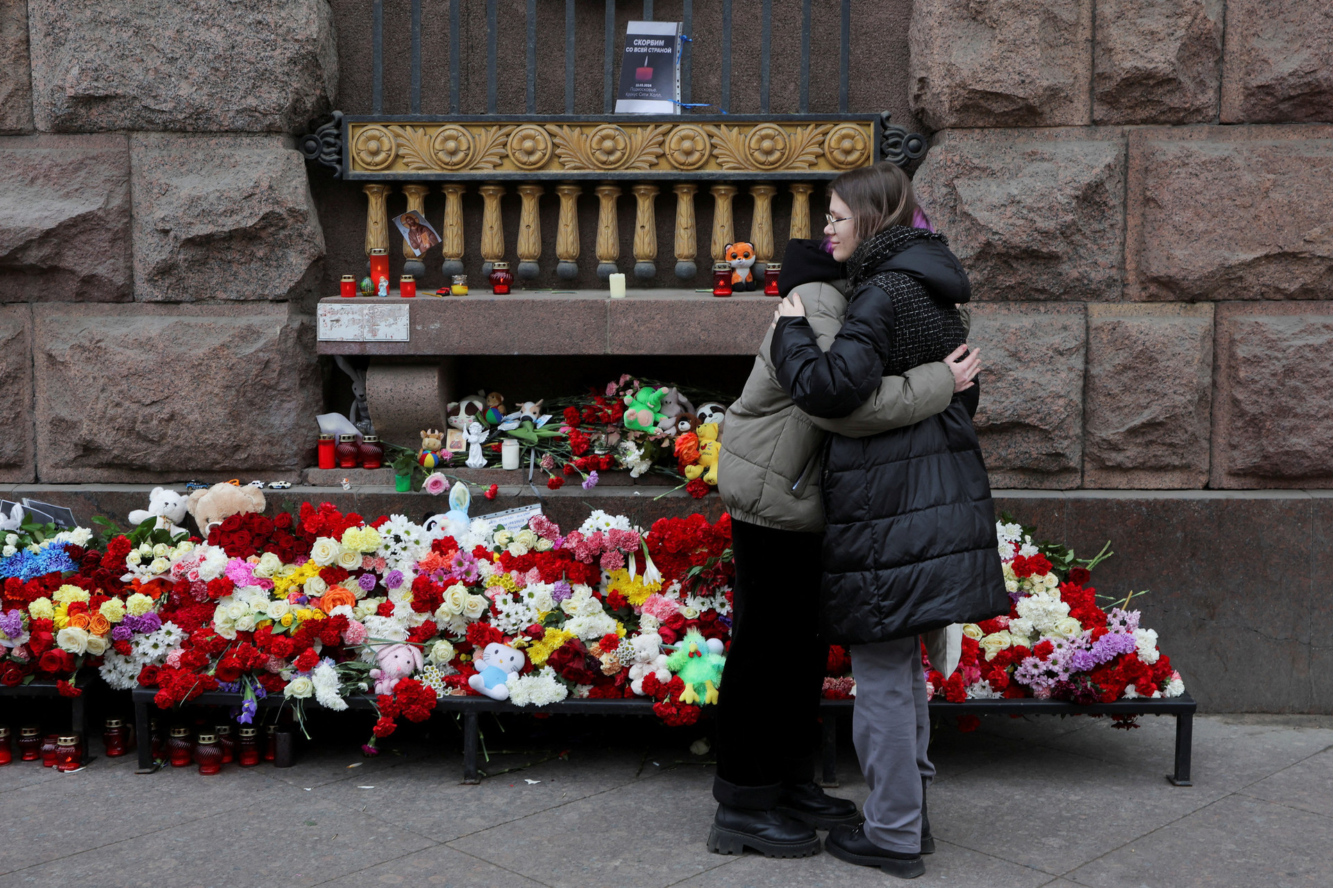 Hai phụ nữ ở thành phố Saint Petersburg trao nhau cái ôm trước khu vực tưởng niệm các nạn nhân vụ xả súng ở nhà hát Crocus City Hall - Ảnh: REUTERS