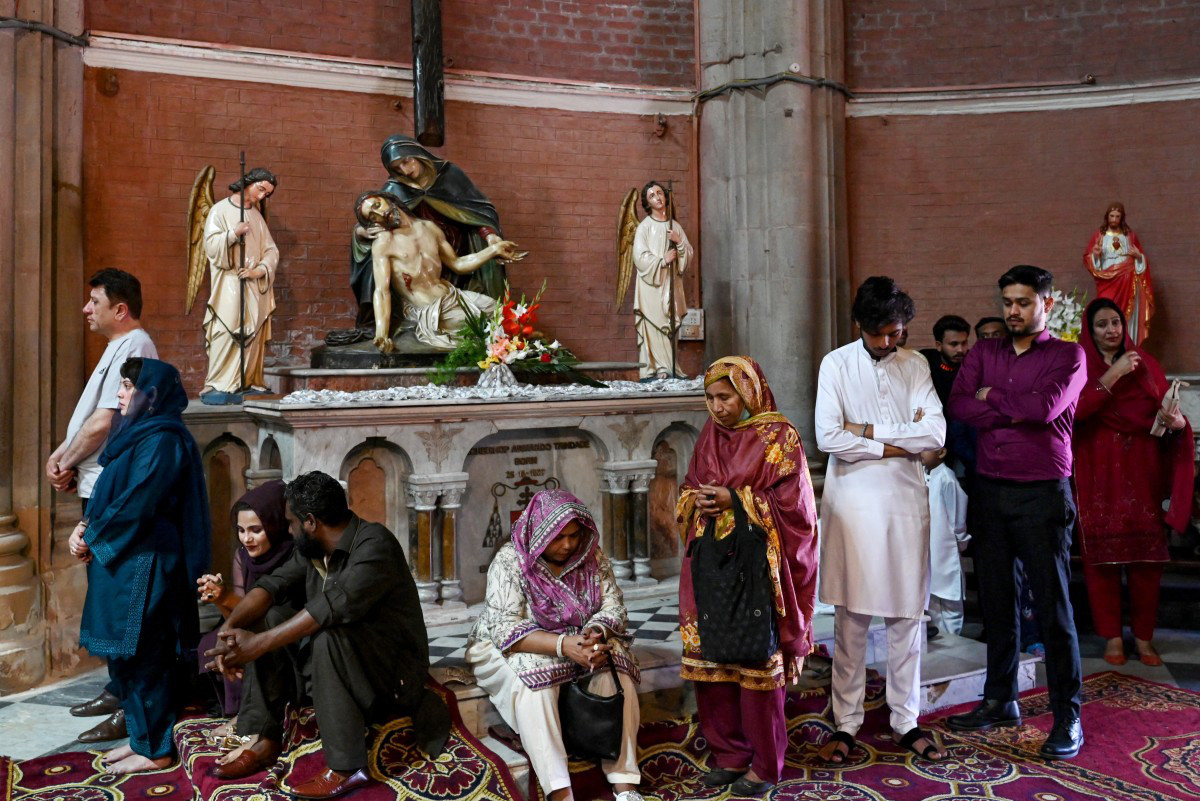 Người dân cầu nguyện bên cạnh bức tượng Đức Mẹ bế xác Chúa Giê-su vào sáng 31-3 ở nhà thờ Thánh Tâm ở Lahore, Pakistan - Ảnh: AFP