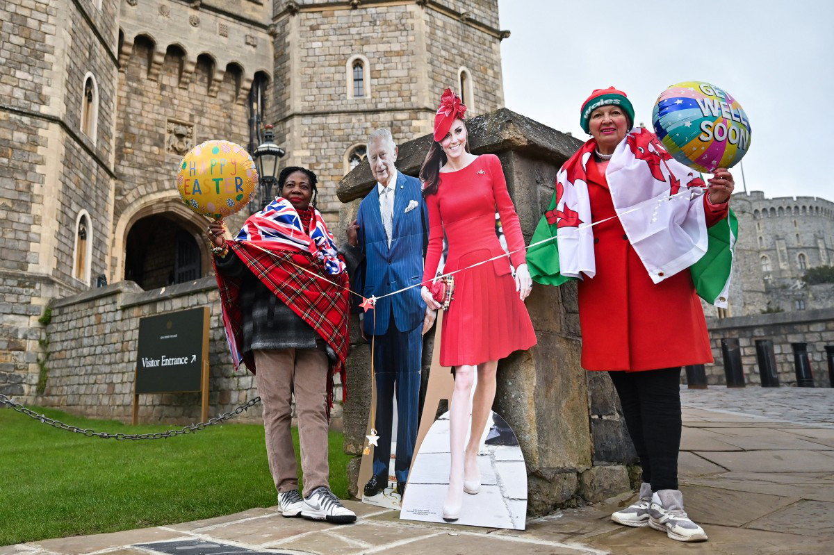 Những người dân tạo dáng bên cạnh ảnh Vua Charles III và Công nương Catherine trước lâu đài Windsor khi gia đình hoàng gia Anh chuẩn bị tham dự Thánh lễ Phục sinh tại nhà nguyện Thánh George, thuộc lâu đài Windsor vào sáng 31-3 - Ảnh: AFP