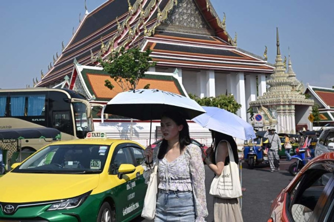 Du khách che ô tránh nóng khi tham quan chùa Wat Pho tại Bangkok hồi cuối tháng 4. Ảnh: AFP