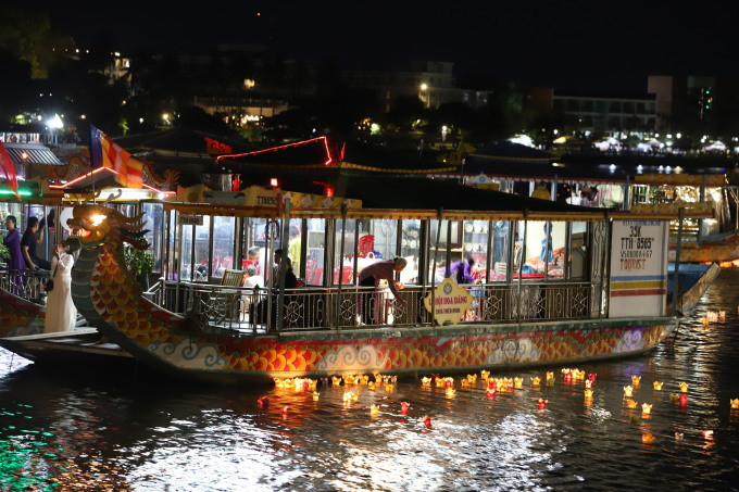 Phật tử ngồi trên thuyền rồng thả hoa đăng xuống sông Hương. Ảnh: Võ Thạnh