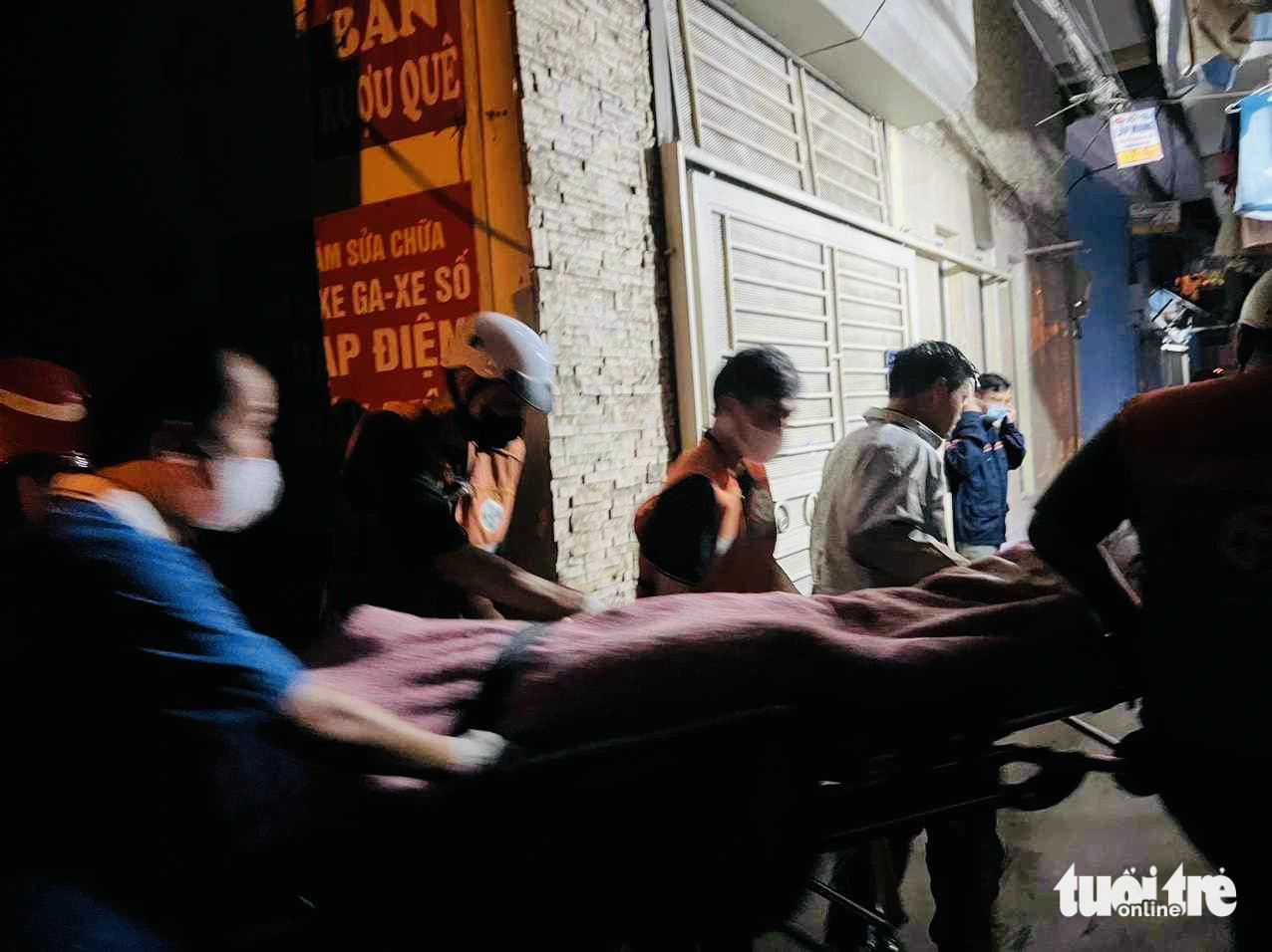 Lực lượng chức năng đưa thi thể một số nạn nhân ra ngoài - Ảnh: MINH THANH