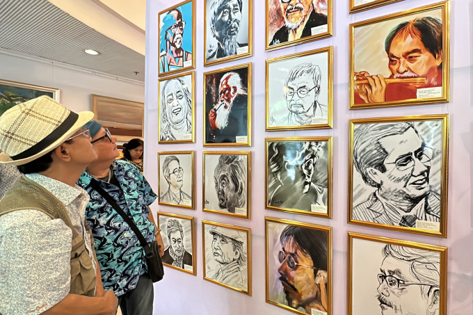 Cựu nhà báo - giảng viên báo chí Huỳnh Dũng Nhân (trái) trước không gian triển lãm tranh chân dung của ông. Ảnh: Mai Nhật
