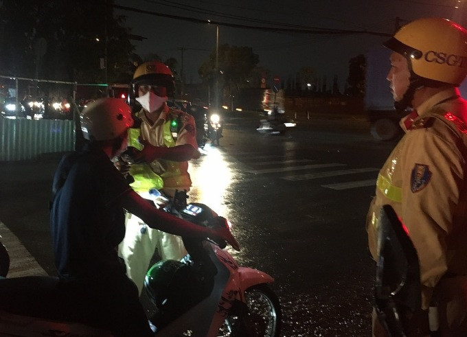 Cảnh sát kiểm tra một người lái xe máy vi phạm nồng độ ở giao lộ Lã Xuân Oai- D2, TP Thủ Đức, tối 2/7. Ảnh: Đình Văn