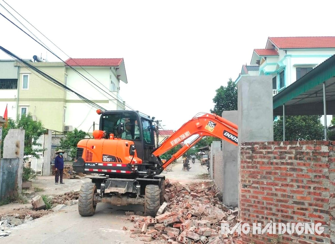 Gia đình bà Bùi Thị Thành tự thuê máy xúc đến phá dỡ tường bao để lấy mặt bằng hiến đất cho địa phương