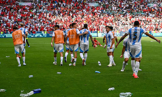 Cầu thủ Argentina bị ném chai lọ khi mừng bàn gỡ hòa 2-2 của Cristian Medina, sau bị tước vì việt vị, ở lượt đầu bảng B bóng đá nam Olympic trên sân Geoffroy-Guichard, thành phố Saint Etienne, Pháp ngày 24/7/2024. Ảnh: AFP