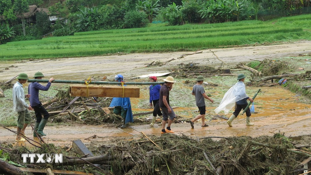 Đưa thi thể được tìm thấy sau cơn lũ dữ ở làng Nủ (Lào Cai) về an táng. (Ảnh: Hồng Ninh/TTXVN)